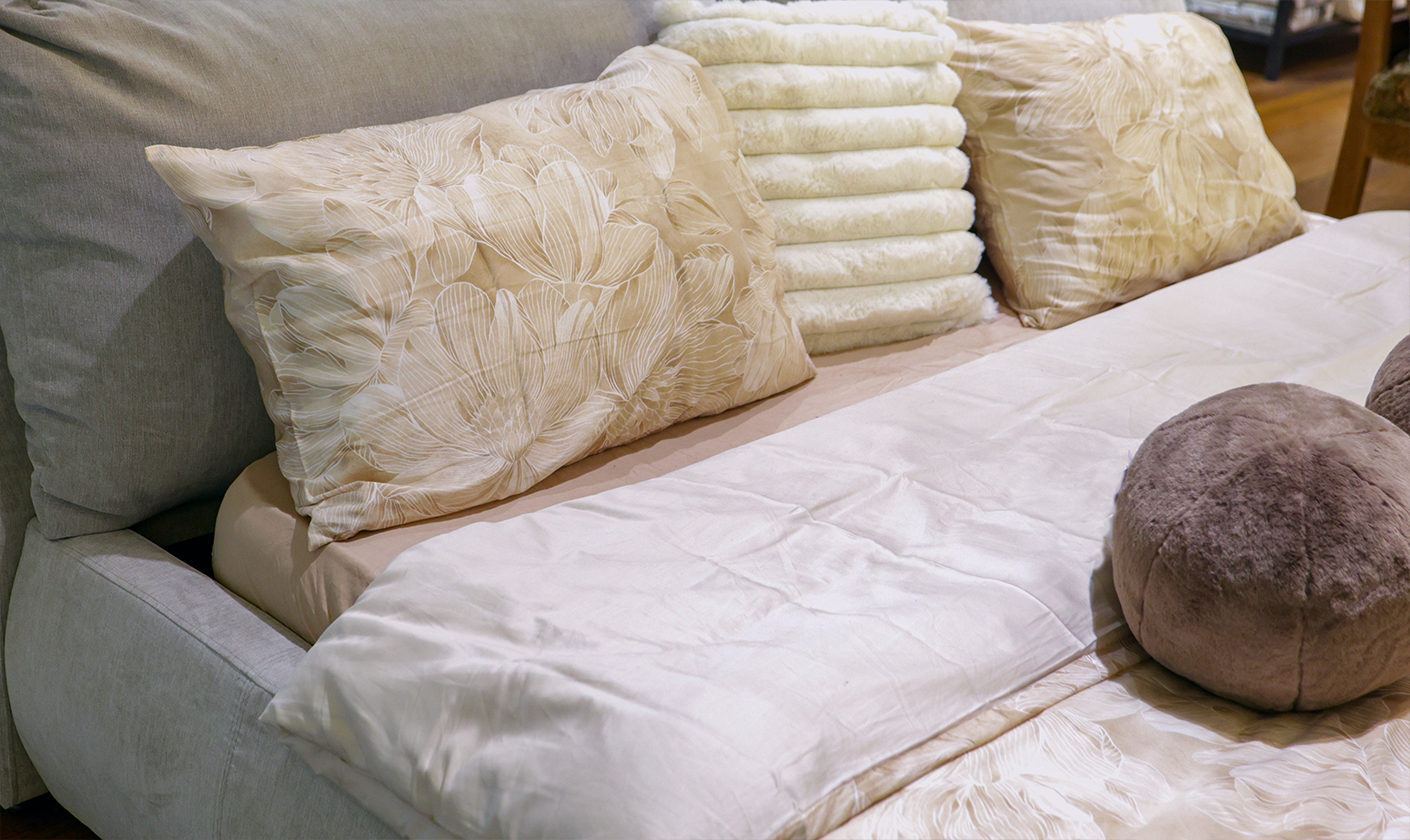 Neutral bedding set with layered pillows creating a calm and cozy bedroom atmosphere.