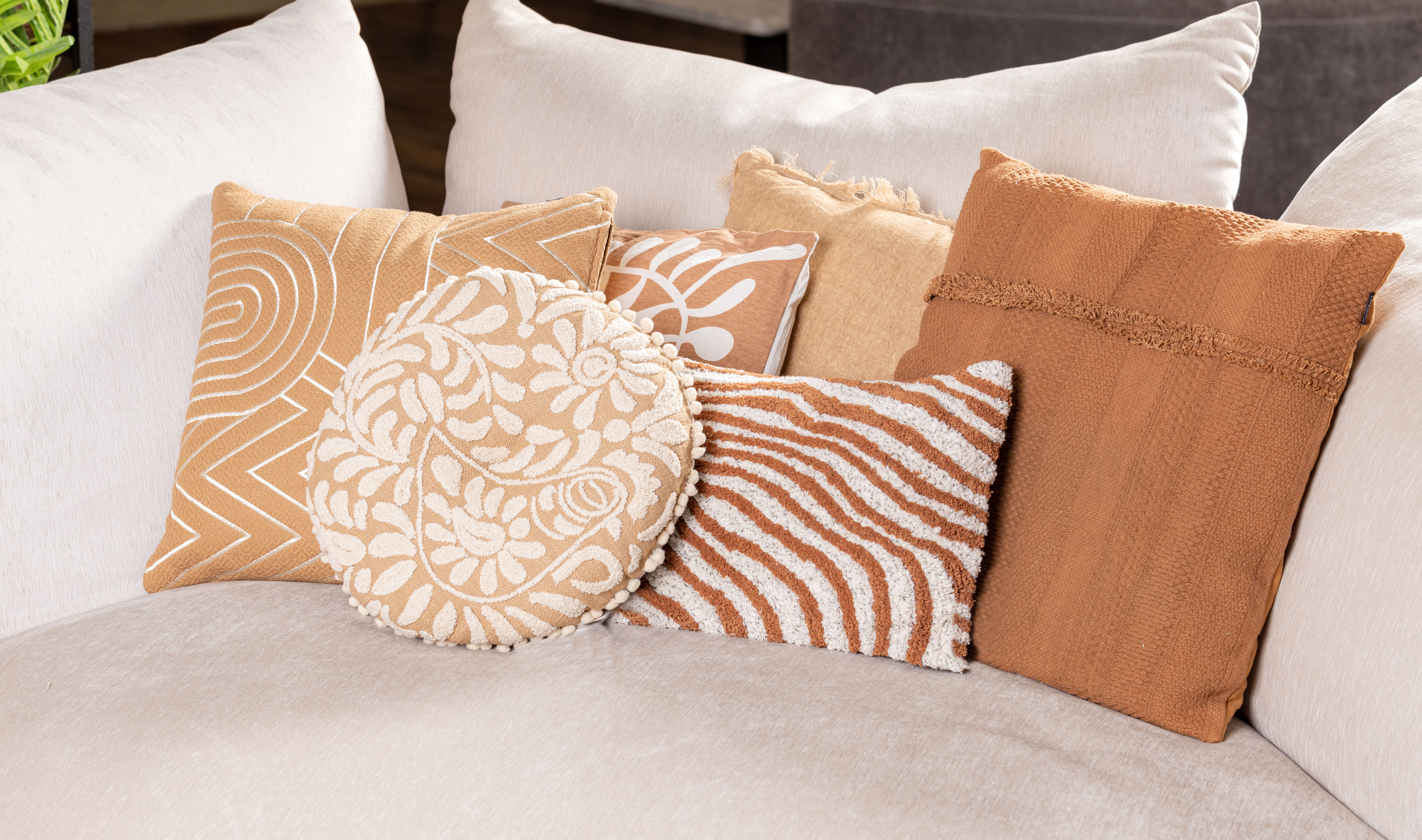 Decorative cushions in beige and terracotta tones styled on a sofa.
