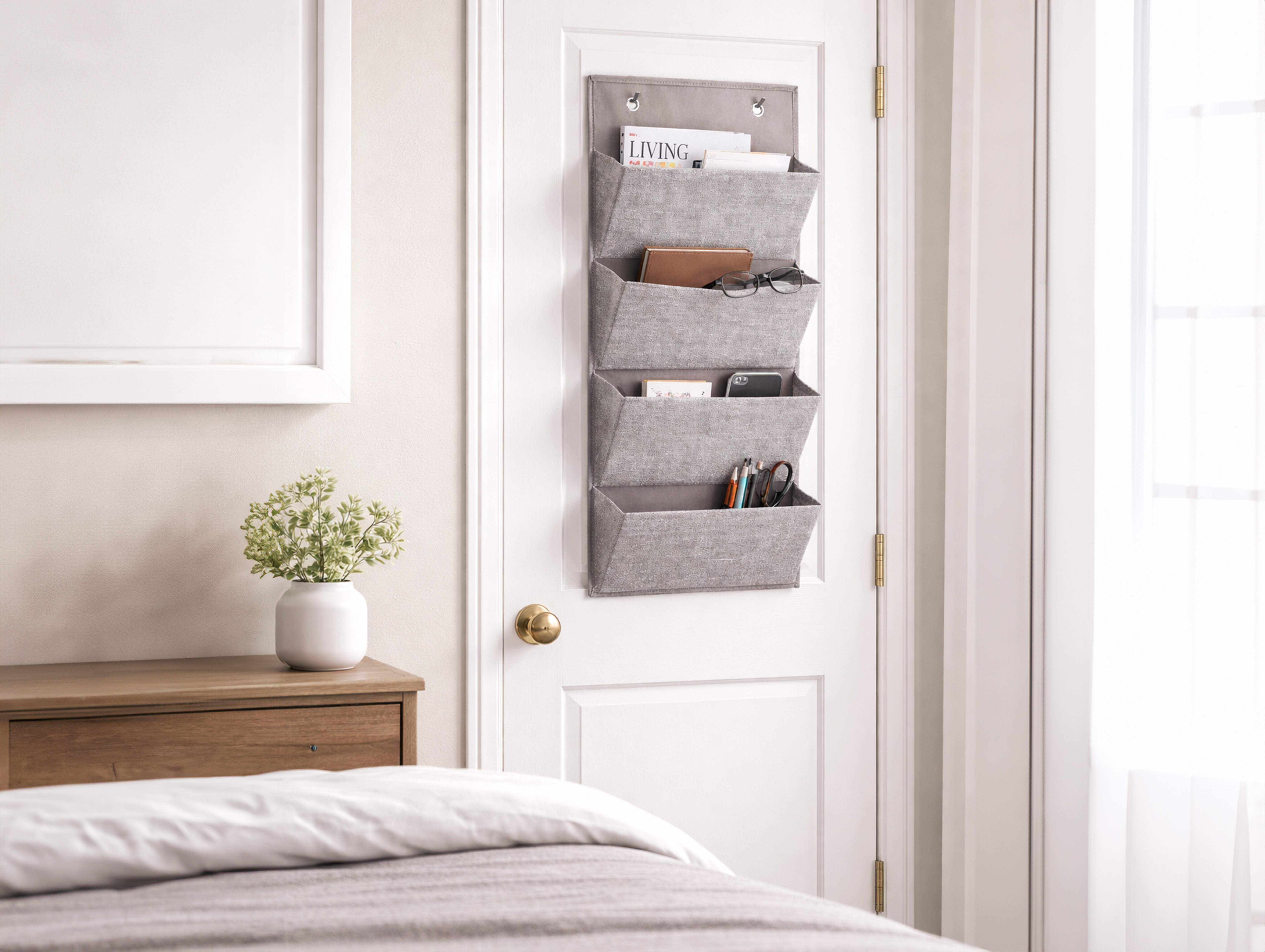 Fabric bedside organizer hanging on a bedroom door with everyday items stored neatly.