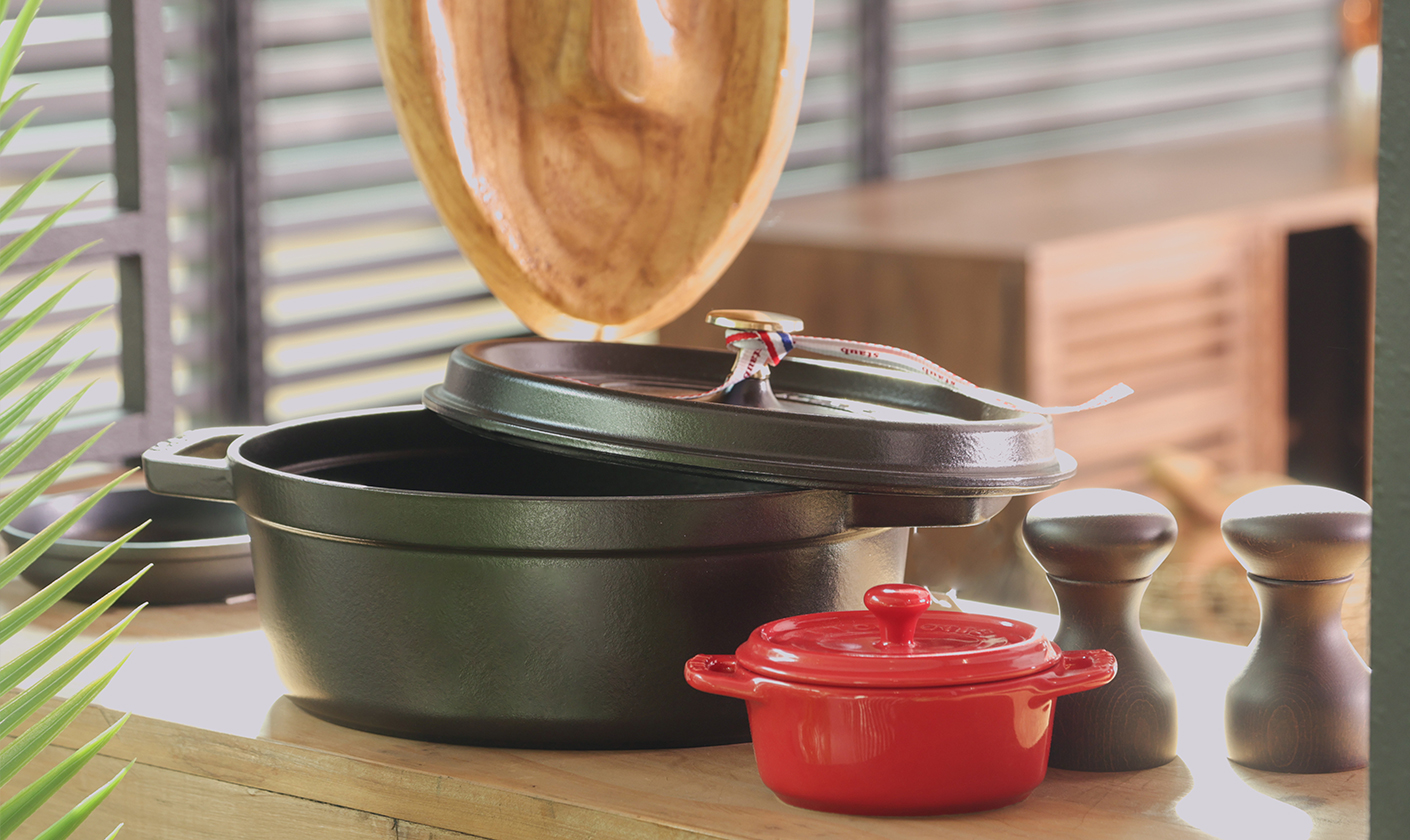 Modern kitchenware including cooking pots and utensils styled on a kitchen counter.