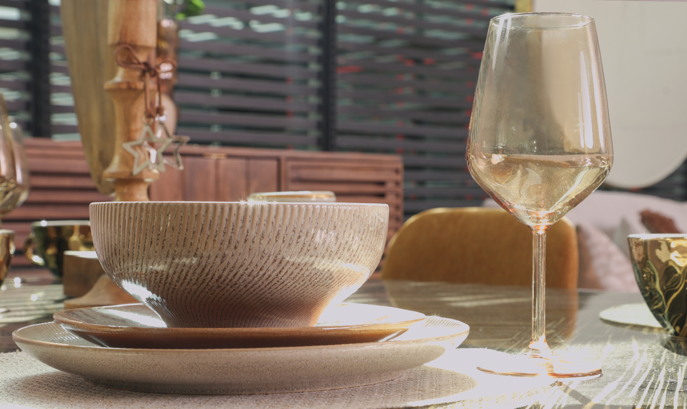 Minimal tableware set with plates, bowls, and glassware arranged on a dining table.