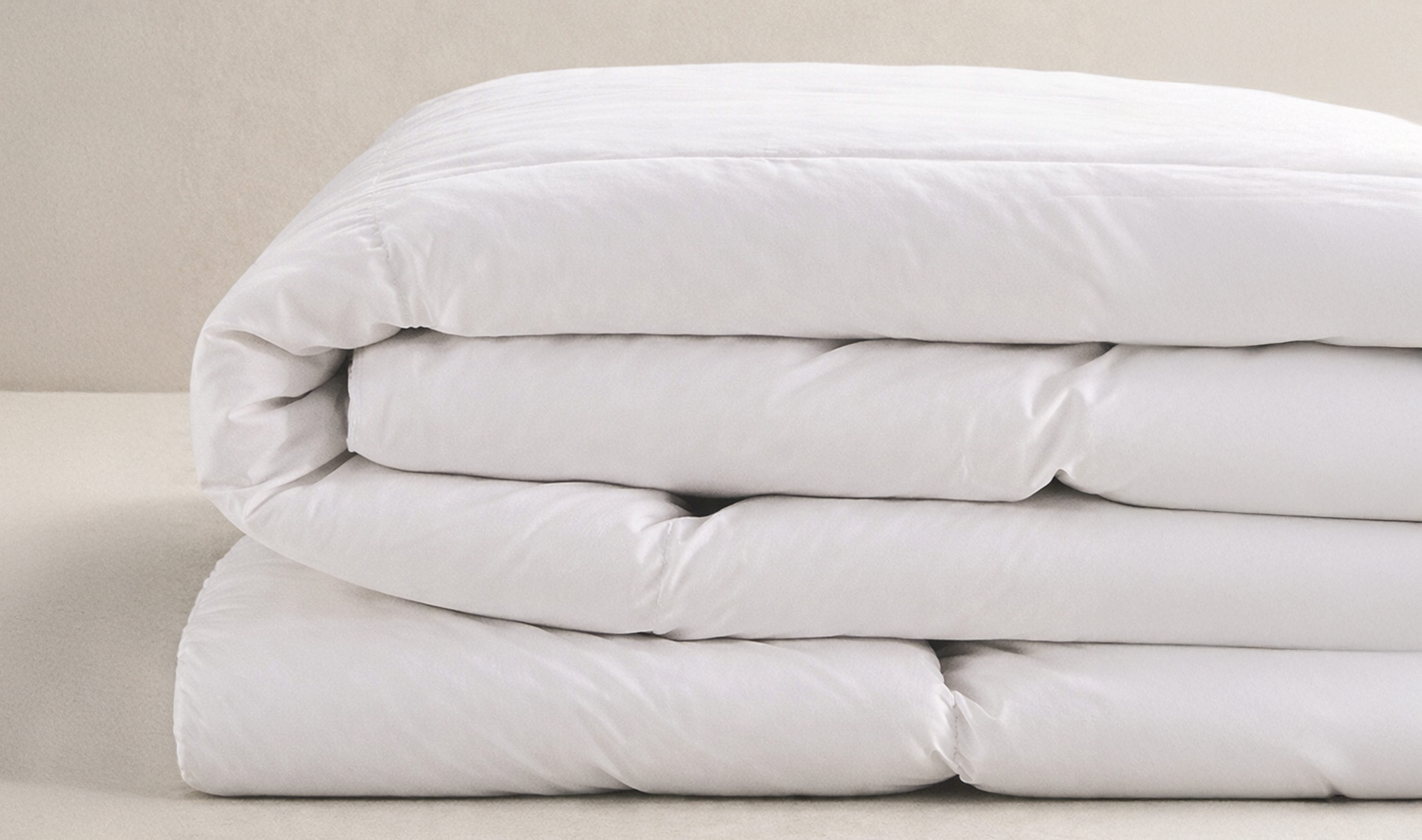 Folded white comforter on bed