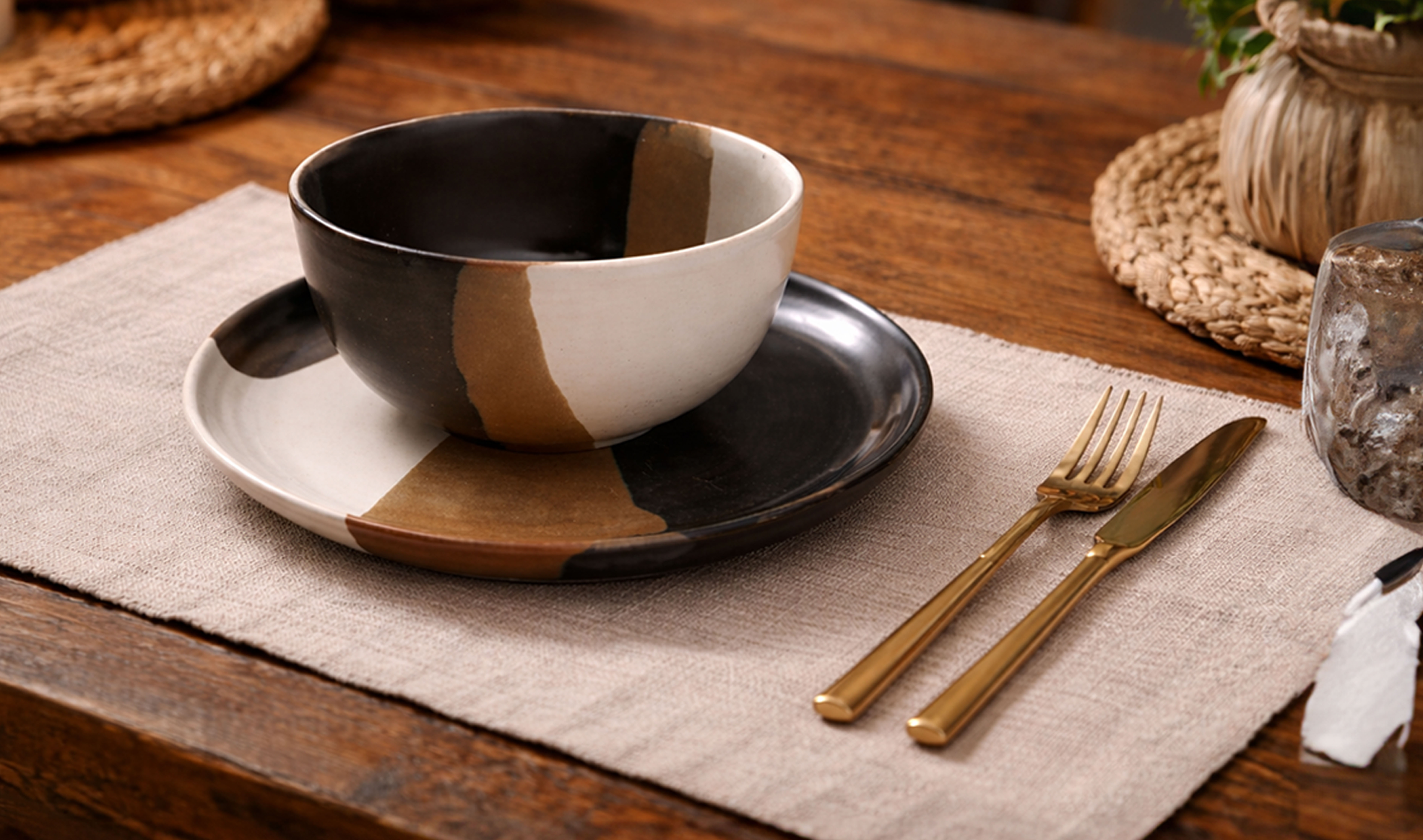 Two-tone ceramic bowl and plate set on a wooden table.
